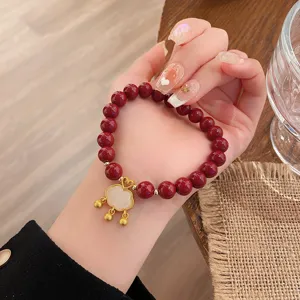 Gros plan détaillé d'un bracelet de perles rouges avec pendentif cadenas doré, élégant.