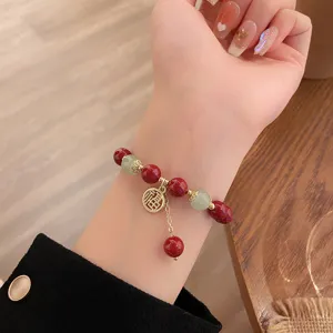 Vue détaillée d'un bracelet de perles rouges de style chinois avec pendentif Fu et jade.