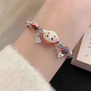 Detailed shot of a cute ceramic lucky cat braided bracelet with bells for women and girls.