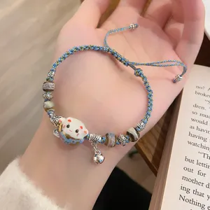 Detailed close-up view of the woven ceramic lucky cat bracelet featuring beads and bell charm.