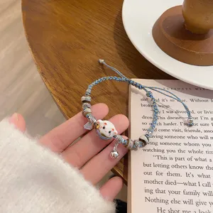 Detailed shot of a braided ceramic lucky cat bracelet with charming beads and cute bell accessory.