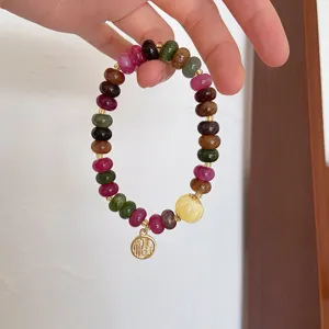 Close-up shot of a colorful gemstone wheel bead bracelet with a lucky blessing charm detail.