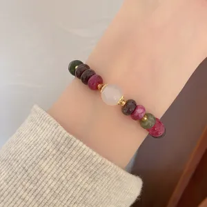 Close-up detail shot of a colorful gemstone wheel bead bracelet with a central white bead.
