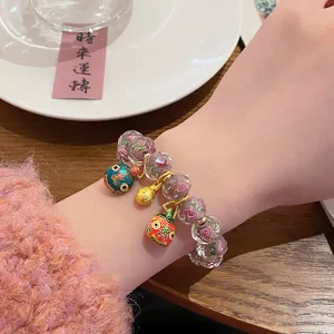 Detailed view of sweet glass rose beaded bracelet with lucky charms on woman wrist.