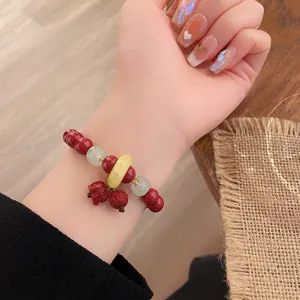 Gros plan detaille du bracelet traditionnel chinois en cinabre et perles de jade sur le poignet.