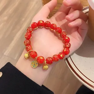 Dettagli in primo piano del bracciale di perline smaltate rosse in foglia d'oro cinese.