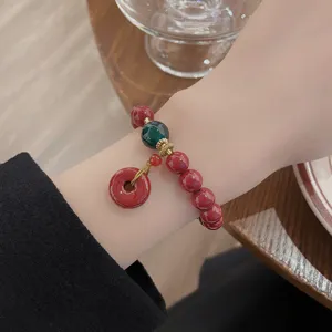 Vue de detail rapproche du bracelet de perles rouges avec perle verte et pendentif style