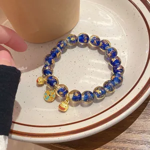 Dettaglio di un bracciale di perle in vetro con foglia d'oro blu, elegante gioiello da polso cinese.