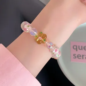 Detailed close-up shot of sweet crystal beaded bracelet featuring floral charms on wrist.