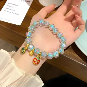 Detailed shot of glazed rose beaded bracelet with cute gold charms on hand, sweet princess style.