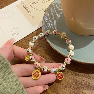 Bracelet de perles cloisonné de style chinois avec charms en émail et accents dorés.