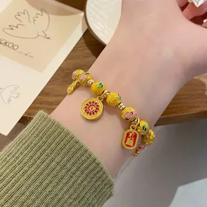 Gros-plan sur le bracelet de perles cloisonne de style chinois avec pendentifs dorés.