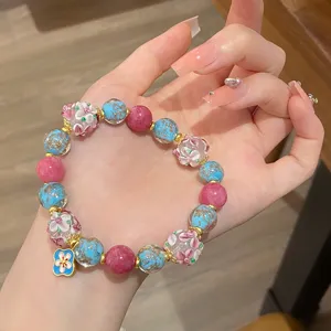 Gros plan détaillé du bracelet de perles de fleurs glacées avec feuille d'or, rose.