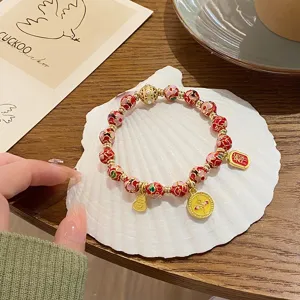 Gros plan détaillé du bracelet de perles en émail cloisonné de style chinois avec charms.