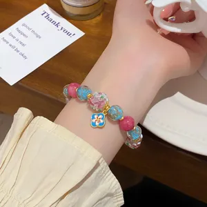 Gros plan détaillé d'un bracelet de perles émaillées avec perles et charm fleuri.