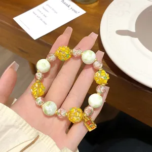 Vue détaillée du bracelet en perles de verre florales avec des perles jaunes et vertes.
