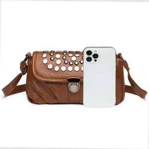 Detailed view of a brown leather shoulder bag featuring metal lock and silver rivets.