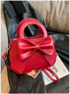 Red women handbag with elegant big bow design, top handle and crossbody strap stylish.