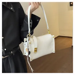 Detailed view of the white leather shoulder bag with gold hardware and cute cow charm.