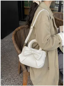 Chic white shoulder handbag for women featuring a stylish large bow and adjustable strap.