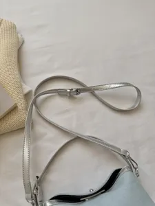 Detail view of a stylish women crossbody shoulder bag with silver metallic strap and modern buckle.