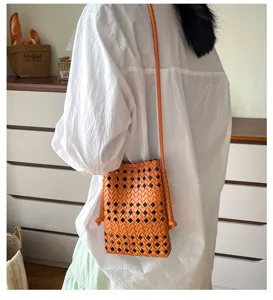 Dettaglio della borsa a tracolla arancione intrecciata traforata dal design unico.