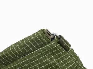 Close up detail of green grid fabric crossbody bag zipper and durable metal hardware hook.