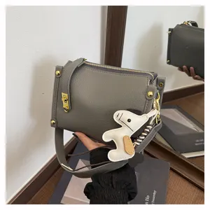Chic grey crossbody bag with wide strap, metal lock and cute horse charm for daily wear.
