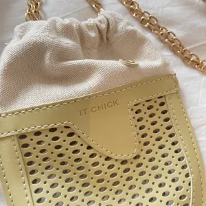 Detail view of the stylish yellow perforated faux leather front pocket and metal chain.