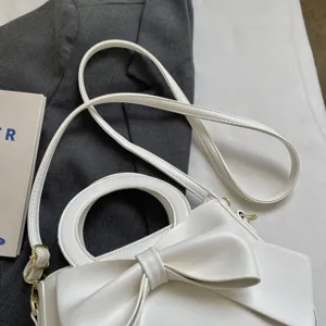 Elegant white leather handbag for women featuring a sweet bow decoration and a stylish strap.