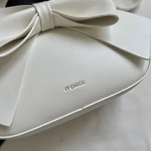 Close-up detail of white elegant women shoulder bag featuring a large chic bow design.