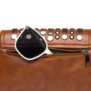 Detailed view of a brown leather women handbag featuring chic metallic studs and sunglasses.