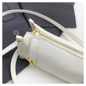 White cylinder crossbody bag detail view, premium leather texture with gold zipper hardware.