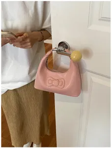 Close-up of the stylish pink leather shoulder bag with a cute bow detail hanging on door.