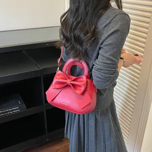 Red shoulder handbag detail view, featuring a sweet bow design, stylish bucket bag style.