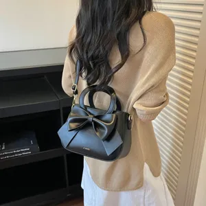 Chic black shoulder handbag featuring a large bow and top handle for sweet everyday style.