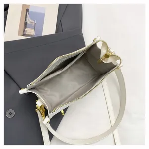 Top view detail of a chic white crossbody bag with a wide strap and neat interior layout.