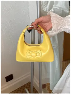 Detailed shot of yellow PU leather underarm shoulder bag with cute stitched bow design.