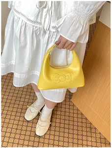 Detail shot of yellow underarm handbag featuring cute 3D bow and zipper closure design.
