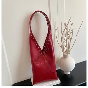 Red patent leather underarm shoulder bag detail with metal grommets and elegant bow tie.