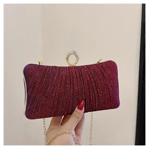 Sparkly wine red evening clutch bag detail, showing pleated texture and elegant ring clasp.