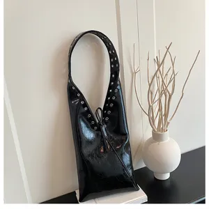 Detail view of a vintage black patent shoulder bag with metallic eyelets and drawstring.