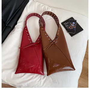 Retro patent leather shoulder bag for women, stylish commuting tote with metal eyelets.