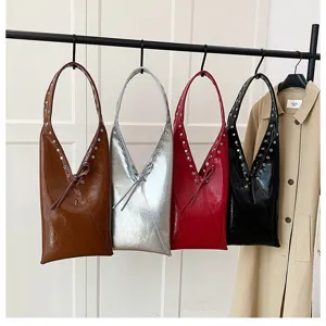 Detailed view of trendy faux leather shoulder bags with metal grommets and knot accents.
