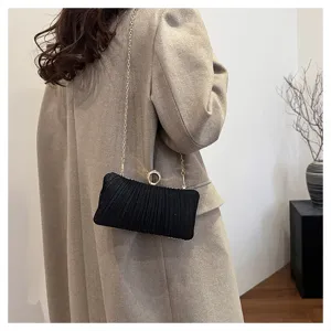 Black pleated evening clutch bag with sparkling rhinestone ring clasp and gold chain strap detail.