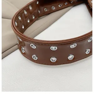 Close-up detail of the stylish brown patent leather shoulder bag with chic metal grommets.