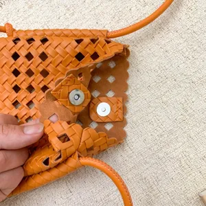 Borsa a tracolla in pelle intrecciata arancione con design traforato e chiusura magnetica.