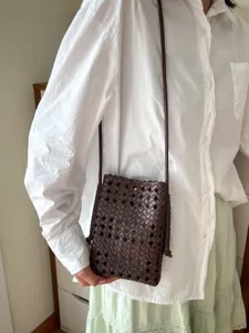 Primo piano dettagliato di una elegante borsa a tracolla in pelle intrecciata marrone.