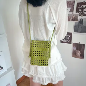 Dettaglio di una elegante borsa a tracolla verde intrecciata, stile casual e chic.