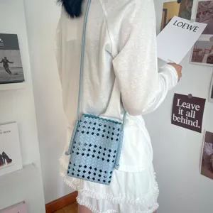 Vista dettagliata di una borsa a tracolla intrecciata azzurra indossata da una modella.